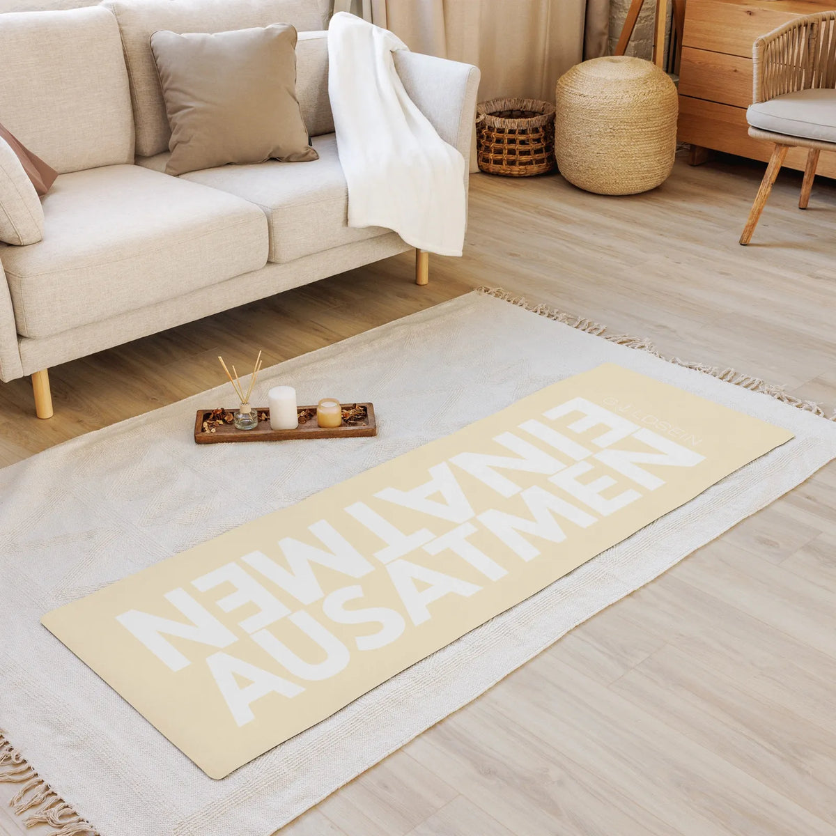 Yogamatte EINATMEN AUSATMEN auf einem Teppich im Wohnzimmer, darauf ein Tablett mit Kerzen