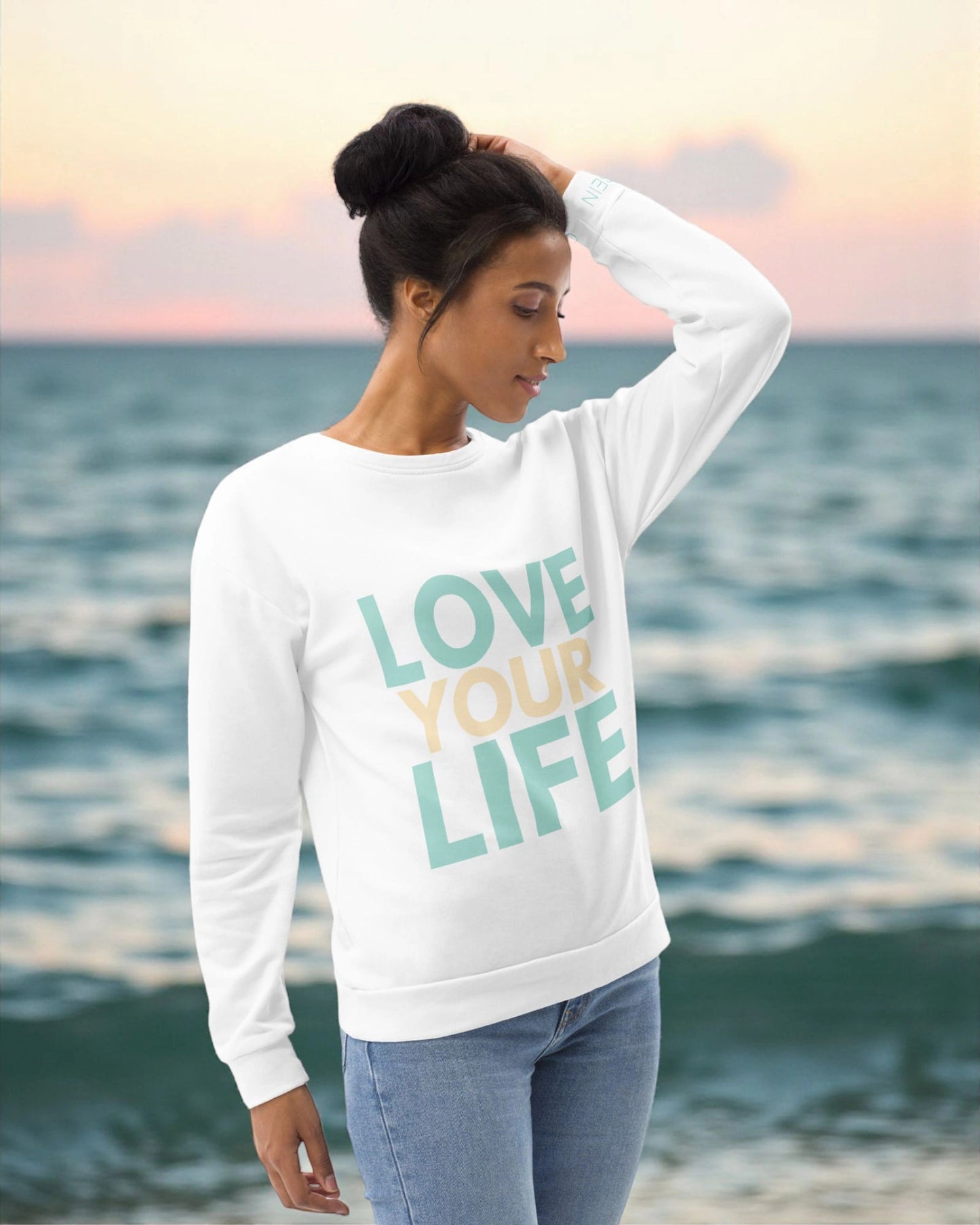 „Goldsein Woman Sweatshirt ‚Love Your Life‘ in Weiß, Türkis und Sand – schmeichelnd und lebendig.“1